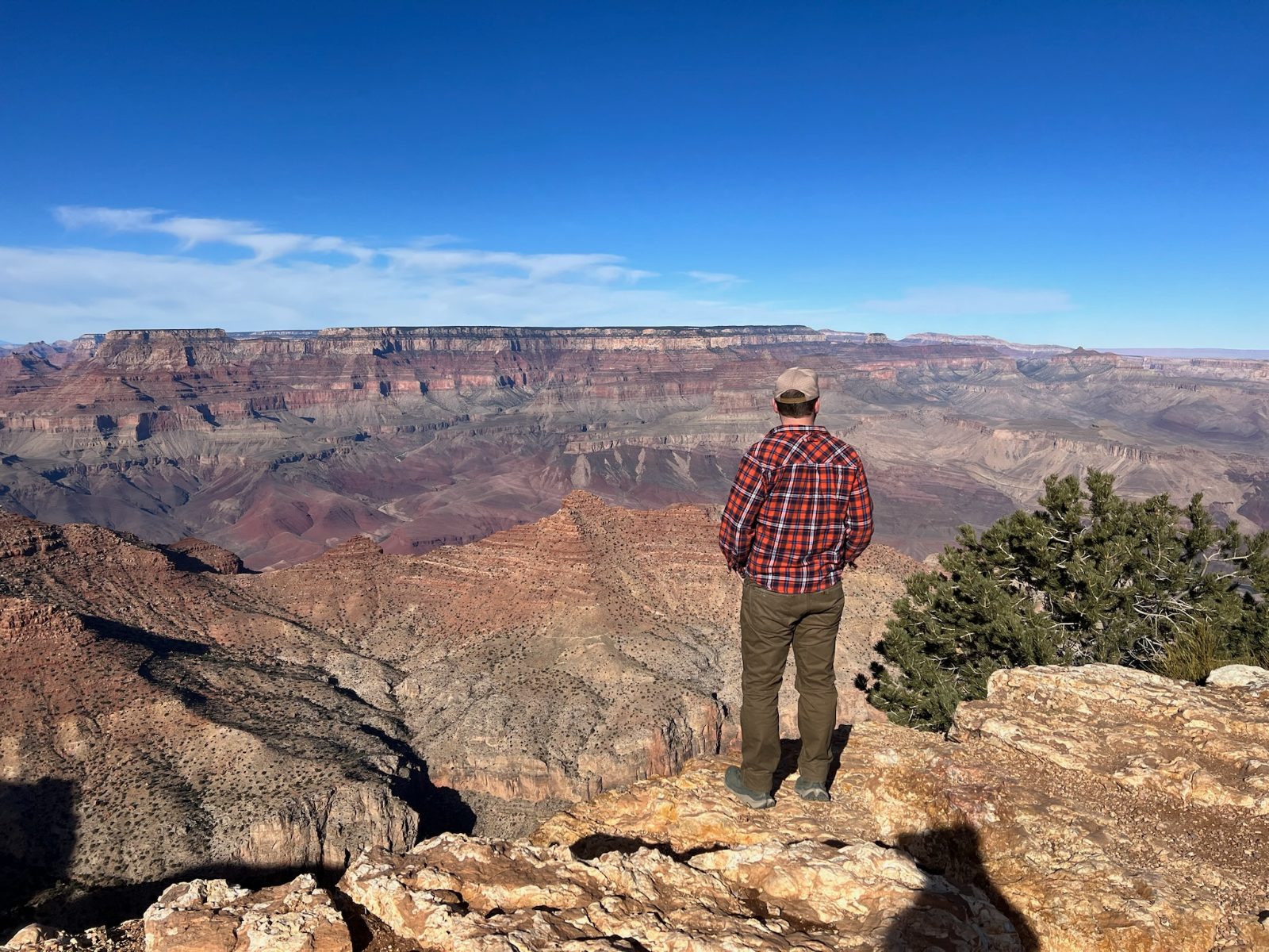 Tony standing at the edge with his back to the camera, looking out across the full width of the canyon