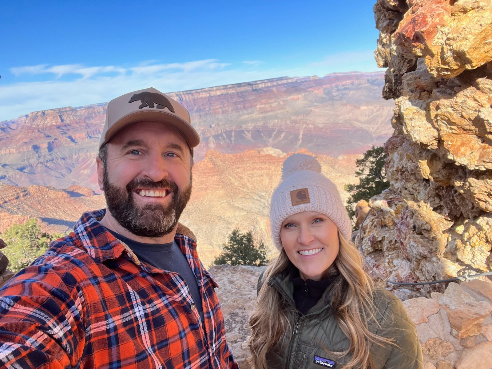Tony and Trisha at the rim at Desert View, canyon walls lit warm behind them, both in cold-weather layers
