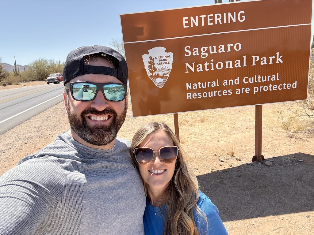 Tony and Trisha at the brown Entering Saguaro National Park sign on the roadside